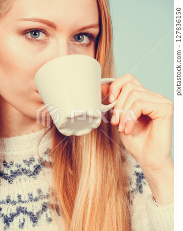 Blonde woman drinking hot drink from cup 127836150