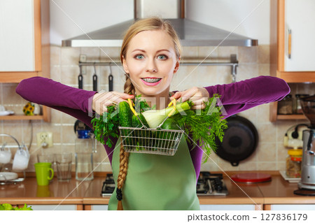 Woman in kitchen having vegetables holding shopping basket 127836179