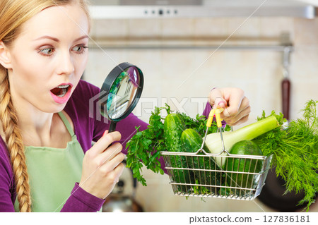 Woman looking through magnifier at vegetables basket 127836181