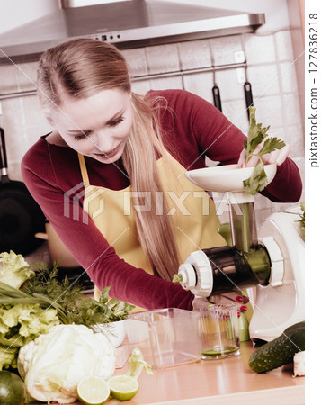 Woman in kitchen making vegetable smoothie juice 127836218