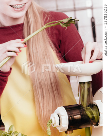 Woman in kitchen making vegetable smoothie juice 127836219