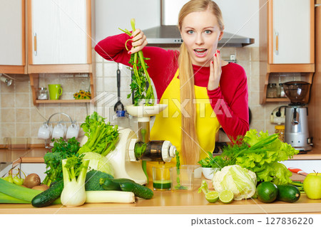 Woman in kitchen making vegetable smoothie juice 127836220