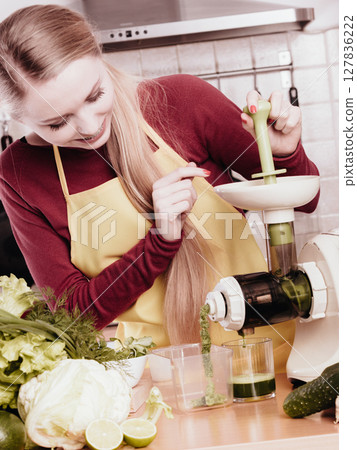 Woman in kitchen making vegetable smoothie juice 127836222