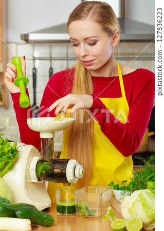 Woman in kitchen making vegetable smoothie juice 127836223