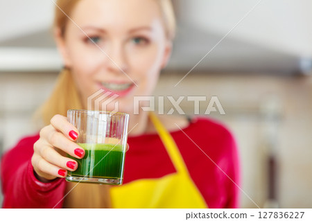 Woman in kitchen holding vegetable smoothie juice Woman in kitchen holding vegetable smoothie juice 127836227