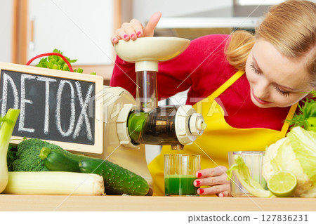 Woman in kitchen making vegetable smoothie juice 127836231