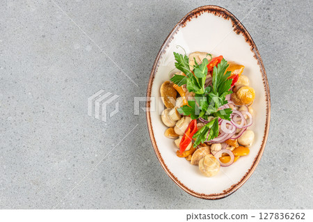 A marinated mushroom salad with red onion rings, chili pepper slices, parsley, and a light dressing served in an elegant oval dish on a gray background A marinated mushroom salad with red onion rings, chili pepper slices, parsley, and a light dressing served in an elegant oval dish on a gray background 127836262