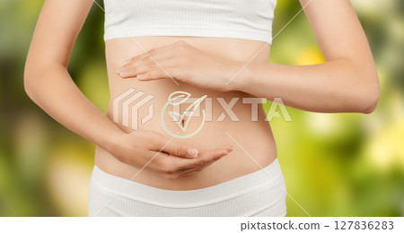 A healthy woman gently cradles her stomach, symbolizing wellness, digestion, and natural care with a glowing gut health icon on a green background A healthy woman gently cradles her stomach, symbolizing wellness, digestion, and natural care with a glowing gut health icon on a green background 127836283