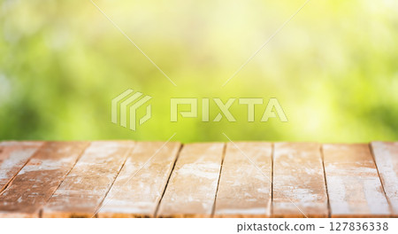 A weathered wooden table with faded planks stands against a soft, blurred green background, ideal for showcasing food, products, or seasonal outdoor concepts A weathered wooden table with faded planks stands against a soft, blurred green background, ideal for showcasing food, products, or seasonal outdoor concepts 127836338