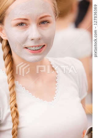 Happy young woman having mud mask on face Happy young woman having mud mask on face 127836369