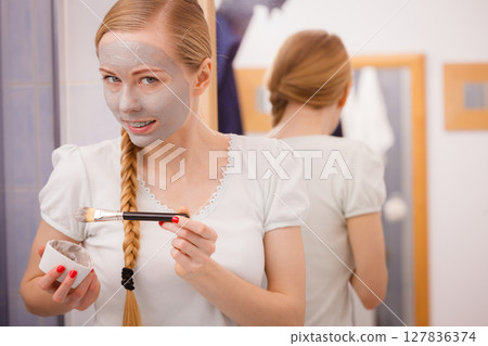 Woman with grey clay mud mask on her face Woman with grey clay mud mask on her face 127836374
