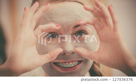 Woman with clay mud mask having fun 127836376