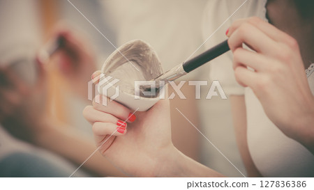 Female hand holding clay mud mask and brush. Skin care. Female hand holding clay mud mask and brush. Skin care. 127836386