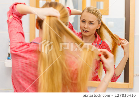 Woman combing her long hair in bathroom 127836410
