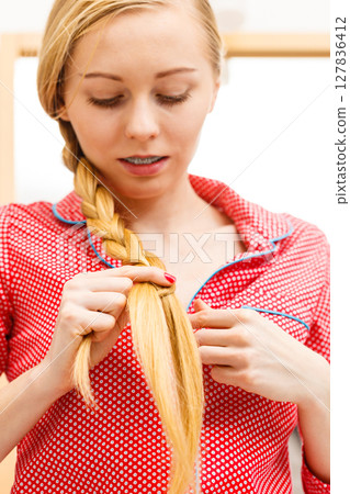 Woman doing braid on blonde hair Woman doing braid on blonde hair 127836412
