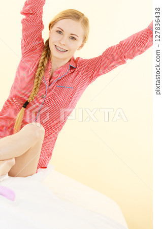 Sleepy woman wearing pajamas holding clock Sleepy woman wearing pajamas holding clock 127836438