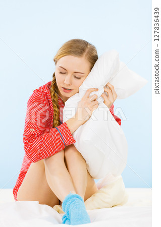 Young woman wearing pajamas hugging soft pillow Young woman wearing pajamas hugging soft pillow 127836439