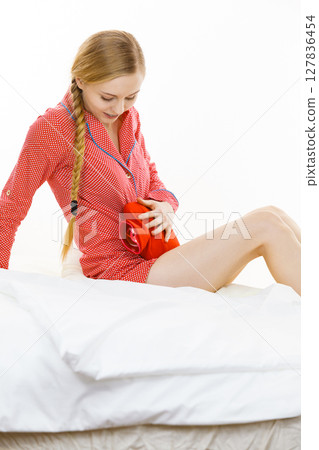 Woman feeling stomach cramps lying on bed Woman feeling stomach cramps lying on bed 127836454
