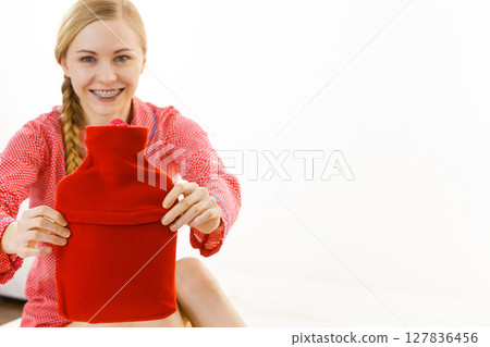 Woman holding warm red hot water bottle Woman holding warm red hot water bottle 127836456