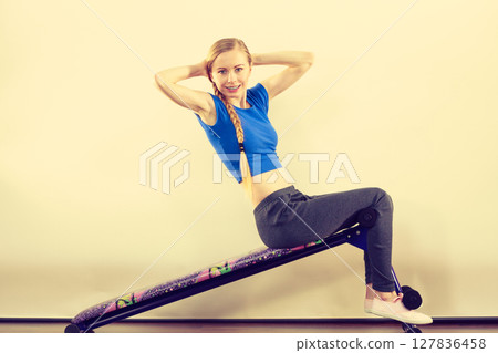 Woman training on bench for sit ups Woman training on bench for sit ups 127836458