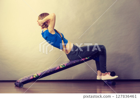 Woman training on bench for sit ups 127836461