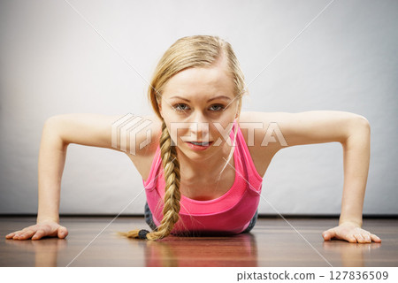 Woman training at home doing push ups 127836509