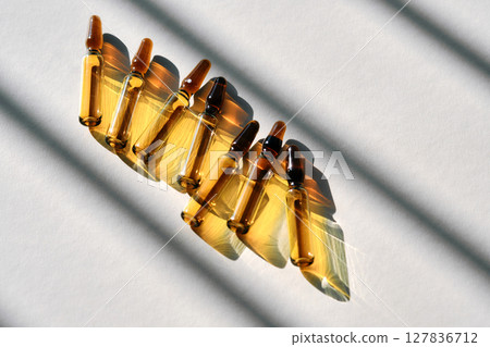 Ampoule serum on a gray background with stripes of chiaroscuro. Ampoule serum on a gray background with stripes of chiaroscuro. 127836712