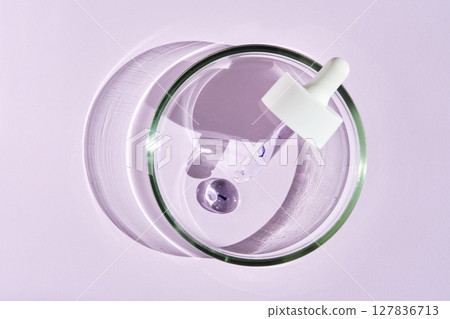 A pipette with a drop of serum in a petri dish on a purple background. 127836713