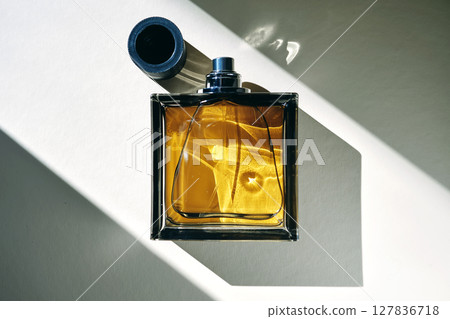 A golden bottle of perfume in a sunbeam. 127836718