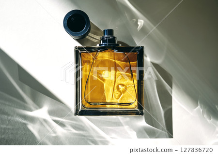 A golden bottle of perfume in a sunbeam. 127836720