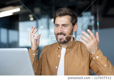 Mature business man participates in online video call using laptop. He gestures enthusiastically while engaged in conversation, conveying ideas during virtual meeting. Captures dynamic business Mature business man participates in online video call using laptop. He gestures enthusiastically while engaged in conversation, conveying ideas during virtual meeting. Captures dynamic business 127837512