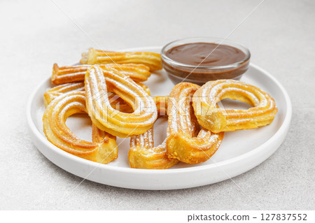 Traditional spanish dessert churros, fried dough pastry and chocolate sause on white background Traditional spanish dessert churros, fried dough pastry and chocolate sause on white background 127837552