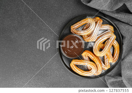 Traditional spanish dessert churros, fried dough pastry and chocolate sause on black background 127837555