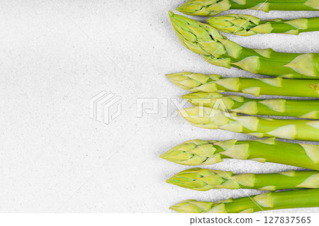 Pile of fresh green asparagus or sparrowgrass stems macro, close up on light textured background 127837565