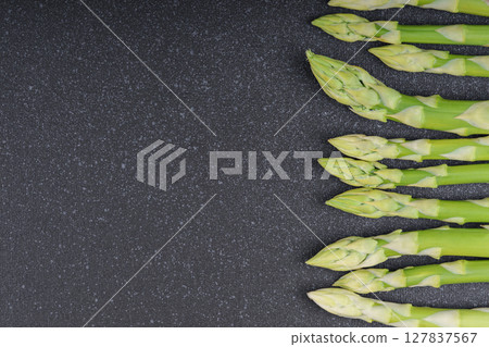 Pile of fresh green asparagus or sparrowgrass stems macro, close up on black textured background 127837567