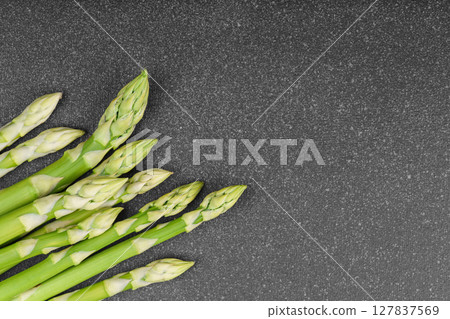 Pile of fresh green asparagus or sparrowgrass stems macro, close up on black textured background 127837569