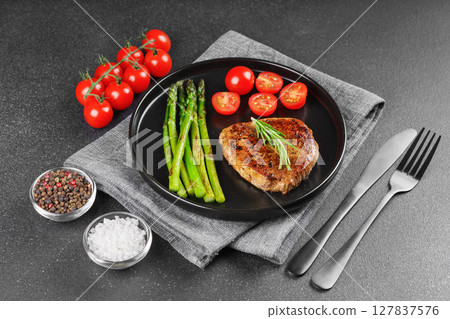 Grilled beef steak with asparagus and cherry tomatoes on black plate, gourmet healthy dinner 127837576