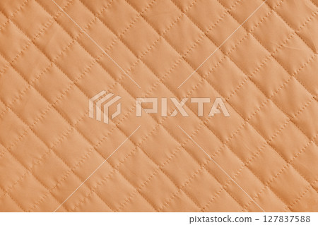 Checkered, diamond stitching pattern, orange quilted fabric background. Blanket stitch texture Checkered, diamond stitching pattern, orange quilted fabric background. Blanket stitch texture 127837588