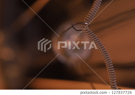 Tungsten filament, an incandescent light bulb, macro view, Metal texture in macro, silver wire 127837726