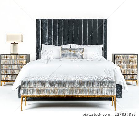 A bed with a black headboard and a white pillow sits in front of a dresser 127837885
