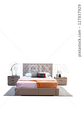 A bed with a white headboard and a pink and orange comforter 127837929