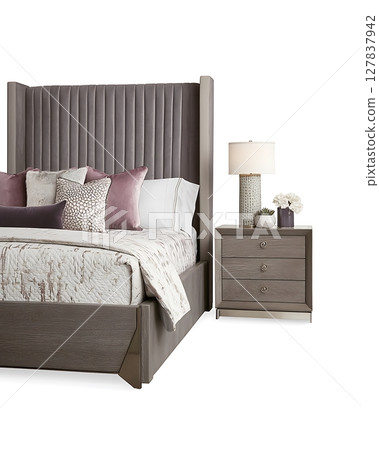 A bed with a grey headboard and pillows and a nightstand with a lamp on it 127837942