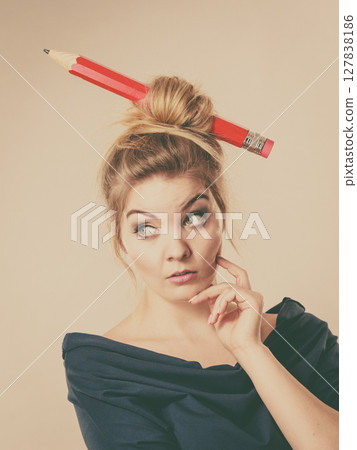 Thinking blonde woman having big pencil in hair 127838186