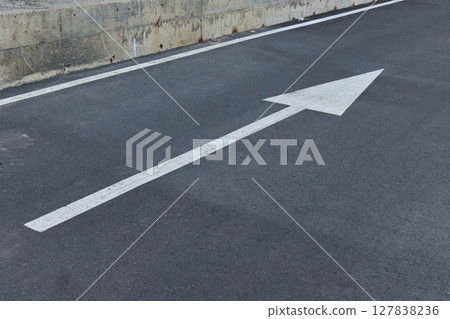 A large white arrow points straight ahead on a asphalt road A large white arrow points straight ahead on a asphalt road 127838236