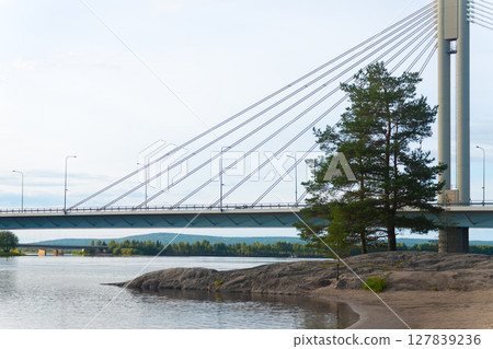 A calm view of a bridge in the city of Rovaniemi. Traveling north, outdoor recreation, polar circle, tourism in Lapland. Bridge with lumberjack candle. River near the forest. Quiet place for relax A calm view of a bridge in the city of Rovaniemi. Traveling north, outdoor recreation, polar circle, tourism in Lapland. Bridge with lumberjack candle. River near the forest. Quiet place for relax 127839236