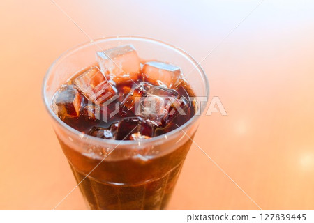 Iced coffee poured into a clear glass on a sunny table Iced coffee poured into a clear glass on a sunny table 127839445