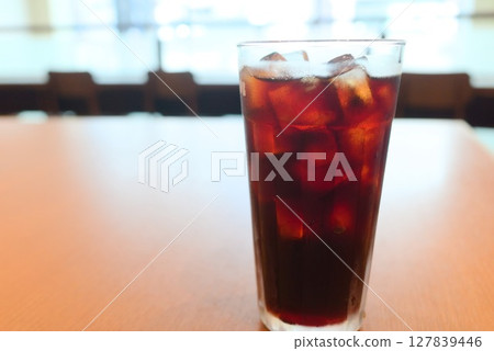 Iced coffee poured into a clear glass on a sunny table Iced coffee poured into a clear glass on a sunny table 127839446