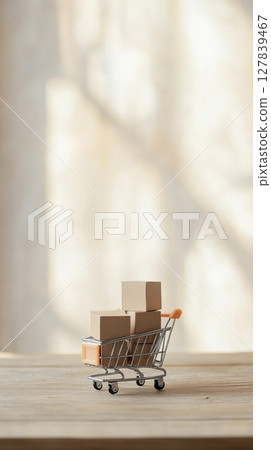 Small cardboard boxes inside a miniature shopping cart sit on a wooden table, representing online shopping, e commerce, and delivery concepts with a bright background 127839467