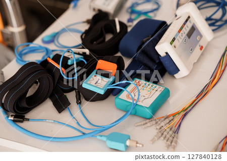 Polysomnography Setup with Electrodes and Sensors on a Table. Blue and Black Medical Devices, Healthcare Diagnostics, Sleep Study Technology. Polysomnography Setup with Electrodes and Sensors on a Table. Blue and Black Medical Devices, Healthcare Diagnostics, Sleep Study Technology. 127840128