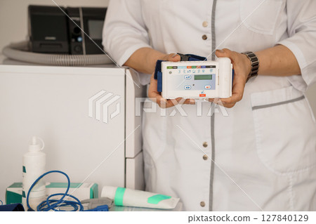 Polysomnography Setup: Medical Professionals Utilizing a Portable Sleep Study Device with Digital Monitor in a Bright Hospital Room 127840129